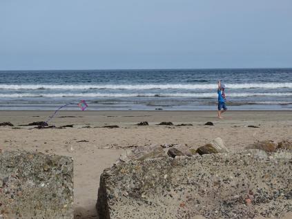 a child pulling a kite along the beach